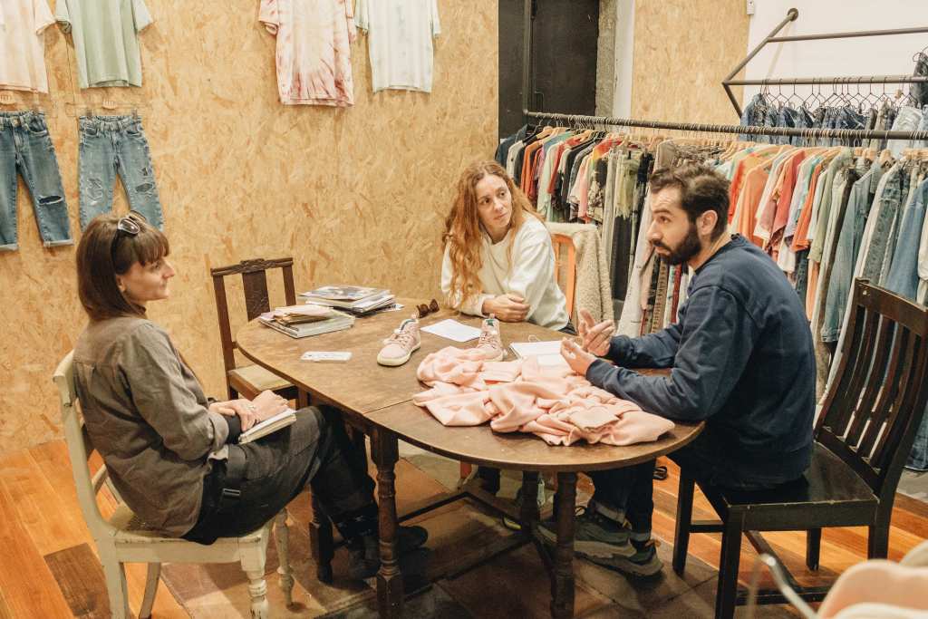 Madlen and Diogo from Minority Denim are sitting across each other at a table in the office, chatting about their collaboration