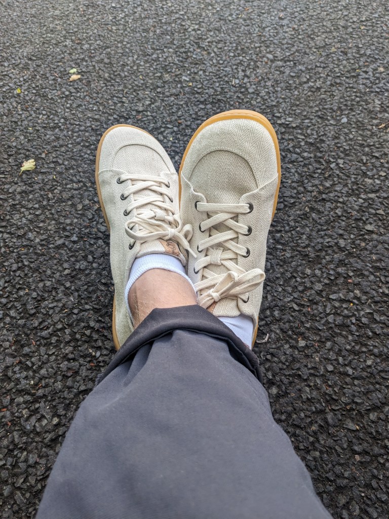 Someone has crossed legs. tHEY ARE WEARING JEANS AND Mukishoes Sand.