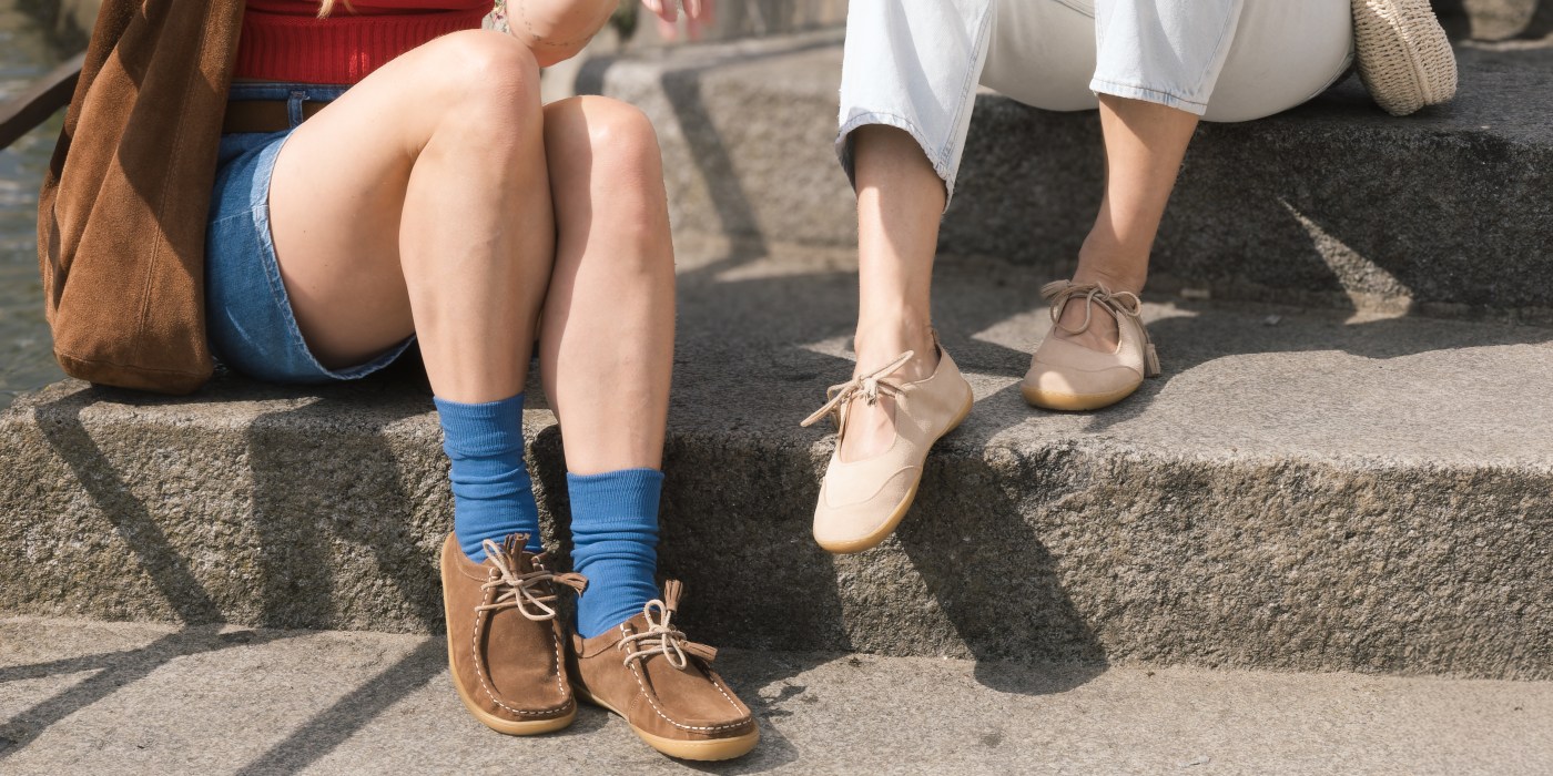 Two people standing in the sun, one is wearing Mukishoes Nomada Terra boat shoes and the other is wearing cream ballet flats Magnolia